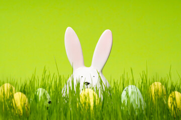 Easter egg hunt. Bunny rabbit and bunch of eggs on meadow and green background. Template for web banner, party flyer or greeting card with copy space.