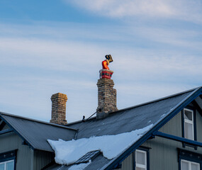 Santa Claus or Santa Claus going upside down through the chimney hole on the snowy roof of a typical Icelandic house, where you can only see from the waist to his boots and legs.