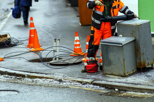 A Worker Uses A Gas Burner To Melt Plastic To Insulate Industrial Wiring In Underground Utilities