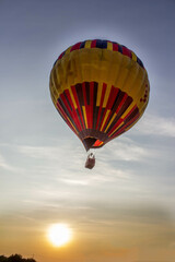 Multicolored balloon flying in the sky at sunset.