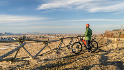 senior male cyclist with a mountain bike on a dirt trail overlooking Colorado foothills