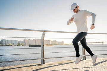 A man running in comfortable sports clothes. Jogging along the embankment in the city.