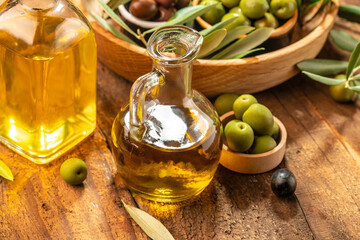 olives berries in wood bowls and oil in glass bottles on a wooden background. Healthy and detox food concept