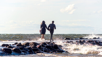 people walking on the breakwater through the waves