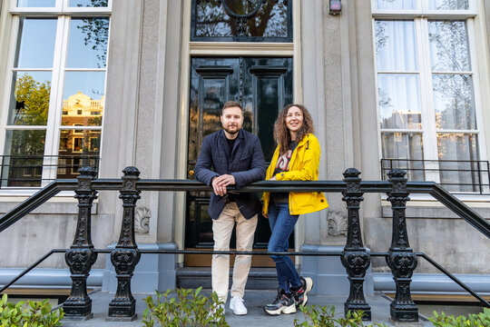 A Young Couple Is Standing On The Porch In Front Of The Entrance To The House