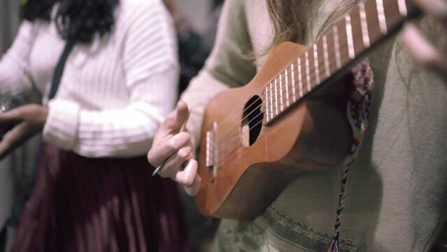 A mexican male musician playing jarana guitar in a traditional music jam session