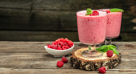 Yogurt smoothie with raspberries in glass on wooden table.