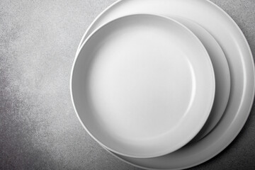 Stack of white porcelain plates and bowls on neutral gray background. copy space