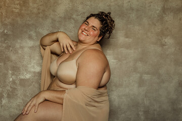 portrait of a plus size woman sitting sideways looking forward smiling