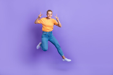 Full body photo of energetic crazy lady jumping show v-sign empty space isolated on violet color background