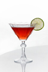 alcoholic cocktail of red color with a slice of lime, in a cocktail glass