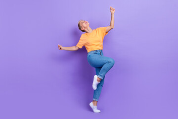 Fototapeta na wymiar Full size photo of optimistic gorgeous nice girl dressed sneakers denim pants dancing having fun isolated on purple color background