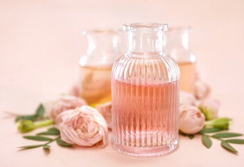 Colorful essential oil bottles  on pink rose background, selective focus, shallow DOF, toned	