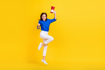 Fototapeta na wymiar Full length photo of pretty lucky lady wear blue shirt jumping high rising fist bullhorn isolated yellow color background