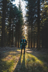 Fototapeta premium Walk through a fragrant and pine forest at sunset in the remote corners of the Beskydy mountains, Czech republic. Man with a backpack on his back in autumn temperatures