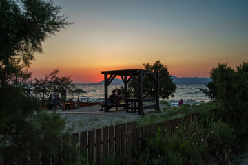Ludzie na wyspie Kos podziwiają zachód słońca nad Morzem Egejskim.