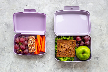 Student meal in purple lunch boxes filled with sandwich and fruits