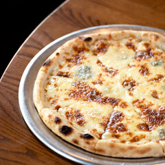 Italian pizza baked intraditional way in oven. Ready dish on metal plate on wooden table. Dark background. View from above. Soft focus. Copy space. 
