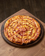 Pizza with cheese and sauce. Pizza is cut into portions on wooden board. Italian Cuisine. Fast food. Wooden table. View from above. Copy space. 