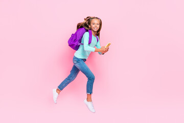Full length profile photo of small excited girl jump rush hold use telephone isolated on pink color background