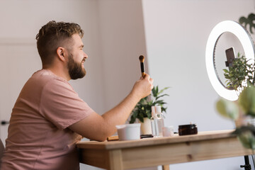 Male beauty blogger doing his make up and recording a video lesson his with mobile phone - vlog,...