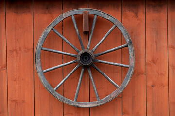 old wooden wagon wheel hanging on a red barn wall