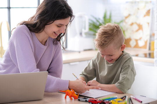Work from home and family education, Mom and son using remote access technology for learning and work, woman works on laptop, child writes in textbook