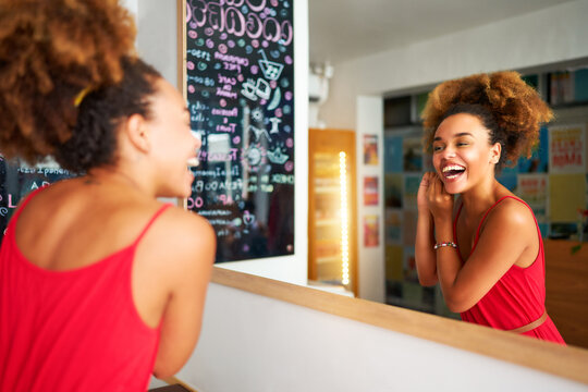 beautiful young black brazilian afro woman fixing herself in the mirror before going out
