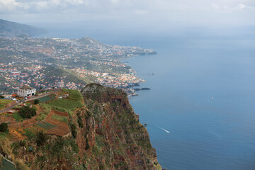 Fototapeta na wymiar Amazing panoramic view of madeira island with mountains, city, houses, agro, ocean and boat. View from the observation deck Cabo Girão Skywalk