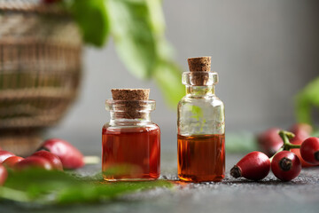 Two bottles of rosehip seed oil with fresh rosehips