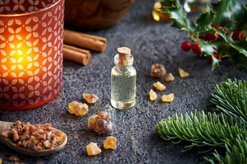 Fototapeta na wymiar Christmas essential oil with myrrh and frankincense resin, holly, cinnamon and fir