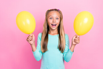 Fototapeta na wymiar Portrait of positive excited girl toothy smile arms hold yellow balloons isolated on pink color background
