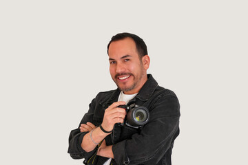 fotógrafo hombre latino sonriente con chaqueta negra y brazos cruzados en fondo blanco