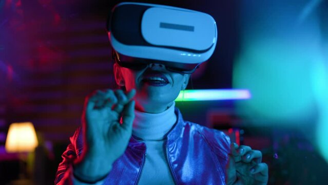 Neon metaverse futuristic concept. Portrait of smiling modern business woman in virtual reality goggles on dark background.