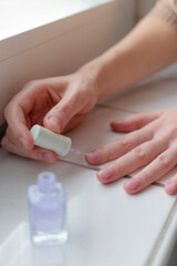 Obraz na płótnie Canvas Woman paints her nails with transparent vegan nail polish.