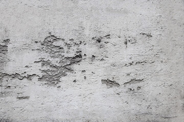 Close-up photo of old plaster on a white wall, which has fallen off in places due to time and weather conditions