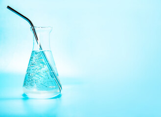 clear liquid with water bubbles in a glass laboratoryy flask, bottle isoalted over blue background