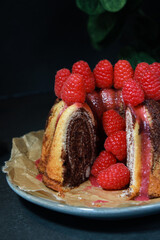close up of home made marble cake with raspberries on top, dark grey background 