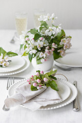 Beautiful table decor for a wedding dinner with a spring blooming apple tree flowers. Celebration of a special event. Fancy white plates, wineglasses