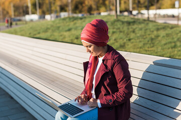 Female muslim arabian student in hijab holding laptop outdoors - freelancer, blogger and diversity concept