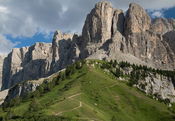 Obraz premium The green hills, and majestic Dolomites mountains in the sunny summer afternoon, pass Gardena, Sella, Italy