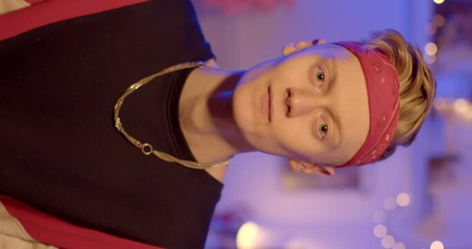 Preparing the camera and model for shooting vertical video. A guy with a bandana on his head and a chain around his neck says information. Evening room.