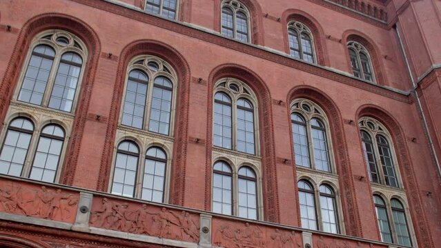 Facade of an old building with high windows. Square glass windows. Burgundy color of the walls, attracting attention.