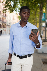 African american tourist on the street writes message on the mobile phone screen