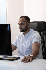 Naklejka premium Boy in white T-shirt working seriously at desk. Concept: office work