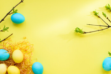 Naklejka na ściany i meble Easter spring holiday flatlay with nest, yellow eggs and blue eggs on yellow background. Easter concept. top view. copy space. flat lay