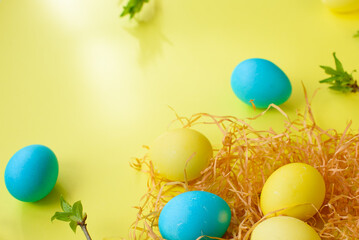Fototapeta na wymiar Easter spring holiday concept with nest, yellow eggs and blue eggs on yellow background. Easter concept. top view. copy space