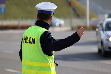 Policjant z lizakiem do zatrzymywania pojazdów kontroluje ruch drogowy