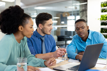 Obraz premium Diverse business people using laptop and discussing in modern office