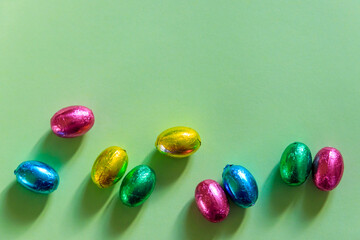 Easter chocolate eggs in foil on green background. Top view